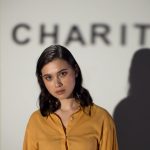 A thoughtful woman stands before a charity-themed backdrop, evoking compassion and volunteerism.